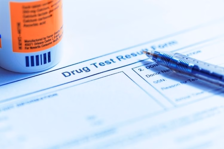Close-up of a drug test results form with a pen and prescription bottle.
